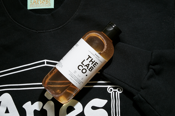 The Lab Co. Darks Laundry Detergent laid next to a section of a black Carhartt t-shirt