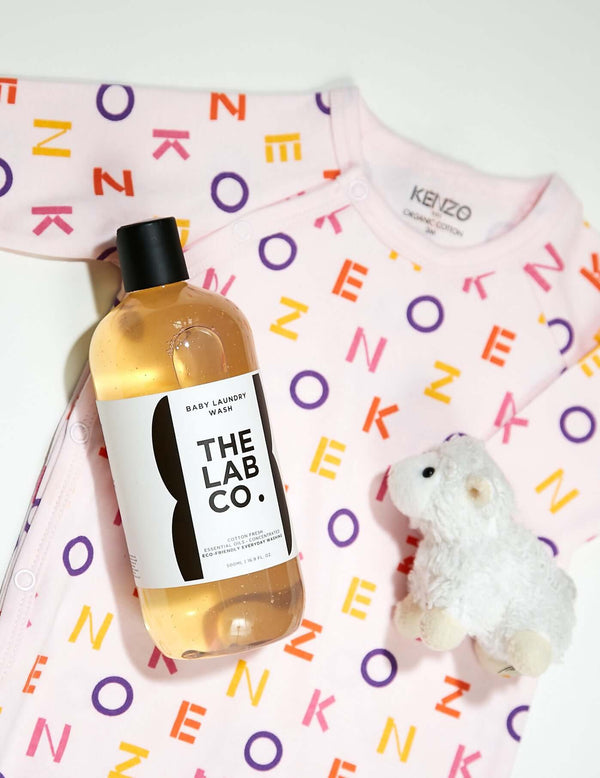 The Lab Co. Baby Laundry Detergent placed on top of a Kenzo baby grow